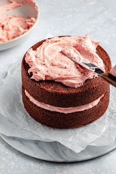 someone is spreading frosting on a chocolate cake