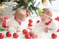 two babies playing with christmas ornaments on the floor