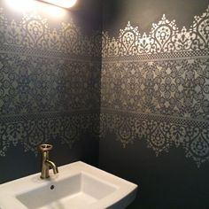 a white sink sitting under a bathroom mirror next to a wall mounted faucet