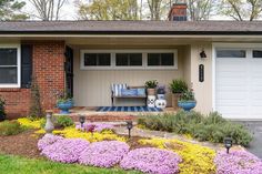 a house with flowers in the front yard and landscaping on the side walk to the garage