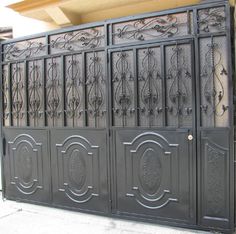 an iron gate is shown in front of a brick wall and door with decorative designs on it