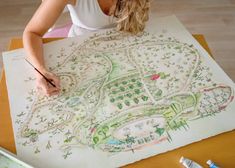 a woman is drawing a map on paper