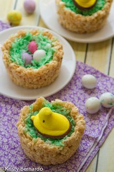 three decorated cupcakes sitting on top of white plates next to an egg in a nest