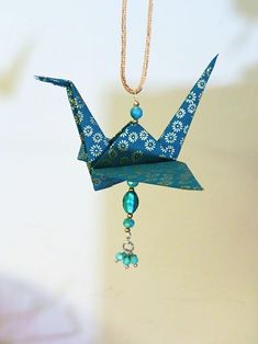 a blue origami crane hanging from a chain with beaded beads on it