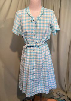 This is a sweet vintage dress from the 50s. No labels or tags. The bust measures 42", waist 32" see measurements below.  Made of turquoise blue, lime green & white plaid cotton. The blue is a little brighter than the photos show.  The dress is not lined.  It is short sleeve with a fitted bodice & flared skirt. The neckline is a V neck with scalloped, pin pleater ruffle trim, along with a little string bow. At the waist seam there are two fabric belt loops & the matching fabric covered belt. The buckle is fabric covered & has discolored with age. Buttons all the way down the front with clear faceted plastic buttons. The buttons are all replacements but are from the same era.  The dress is in very good condition, no damage.  I don't see any spots of stains. A previous owner took up the waist Vintage Blue Summer Dress, Retro Blue Vintage Dress For Spring, Blue Retro Vintage Dress For Spring, Vintage Light Blue Knee-length Dress, Blue Vintage Summer Dress, Summer Vintage Blue Dress, Vintage Blue Daywear Dress, Vintage Light Blue Cotton Dress, Vintage Light Blue Daywear Dress