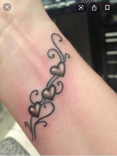 a woman's arm with a tattoo on the wrist and hearts in the middle