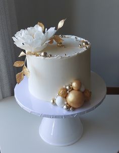 there is a white cake with gold decorations on the top and bottom, sitting on a table