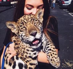 a woman is holding a baby leopard in her arms and it's mouth open