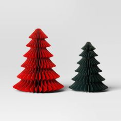 two red and green paper christmas trees sitting side by side in front of each other