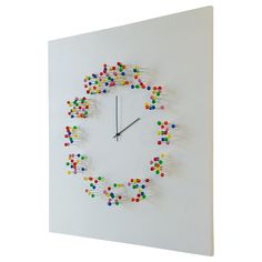 a clock made out of colorful beads on a white wall