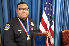 a man in uniform holding an award plaque next to the american flag and blue drapes