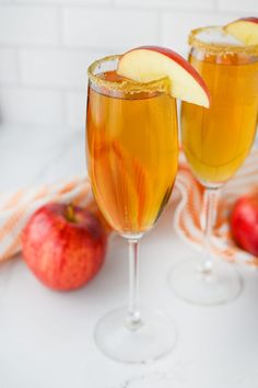 two glasses filled with apple cider on top of a table