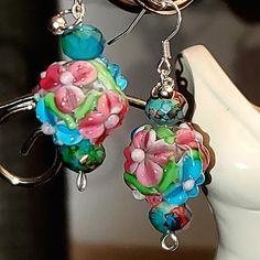 a pair of colorful earrings hanging from a hook on a white mannequin head