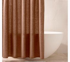 a brown shower curtain hanging on the side of a bathtub next to a toilet