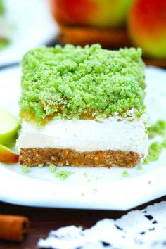 there is a piece of cake on the plate with green and white frosting next to an apple