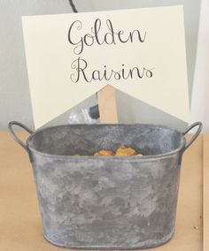 there is a sign that says golden raisins in a metal pot on the table