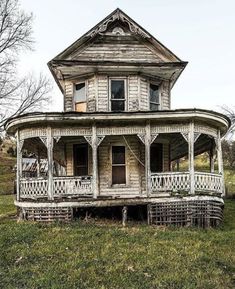 an old run down house sitting on top of a lush green field