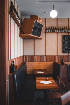 an empty restaurant with wooden booths and black leather chairs