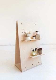 a wooden shelf with various items on it in front of a white wall and floor