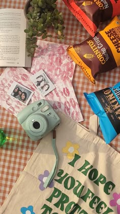 an open book, camera, and other items on a table with a bag that says i hope you're pretty enough