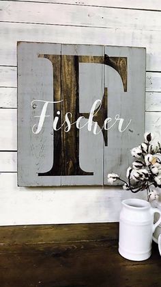 a wooden sign with the letter f painted on it next to two white mugs