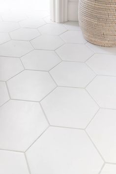 a white floor with hexagonal tiles in the middle and a basket on top