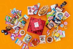 an assortment of snacks and candies arranged in the shape of a heart on an orange background