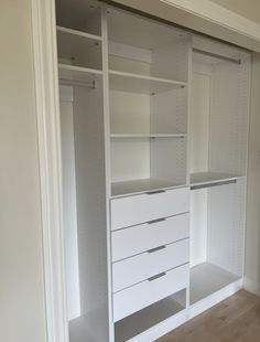 an empty walk in closet with white shelves and drawers