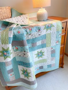 a quilted bedspread on top of a bed with a lamp next to it