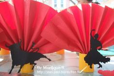 red paper fans with black silhouettes of bulls on them are sitting on a table