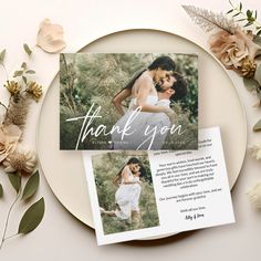 a wedding thank card on a plate surrounded by flowers and greenery with the words, thank you