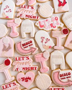 some decorated cookies are laying on a white tablecloth with pink and red lettering that says, let's go night