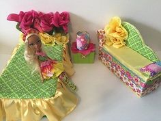 there is a barbie doll sitting next to a box with flowers on it and a gift in the background