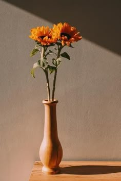 there is a vase with some flowers in it on the table next to a wall