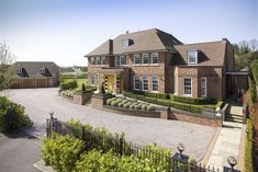 a large brick house with hedges in the front yard and driveway leading to it's entrance