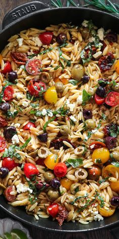 pasta salad with tomatoes, olives and feta cheese in a cast iron skillet