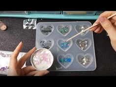 someone is painting hearts with acrylic paint on a tray and holding a brush