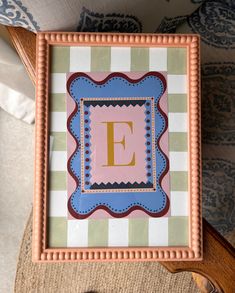 the letter e is painted in pink, blue and green with a scalloped border