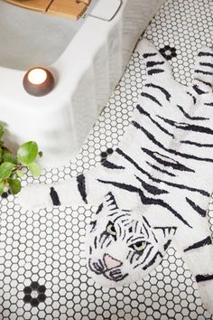 a white tiger rug sitting on top of a bathroom floor next to a bath tub