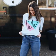 a woman standing in front of a food truck wearing a t - shirt with the word r m u on it