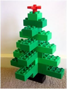 a green lego christmas tree sitting on top of a carpeted floor next to a white wall