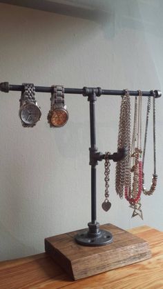 a wooden table topped with a metal rack filled with lots of necklaces and watches