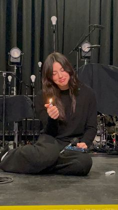 a woman sitting on the floor holding a lit candle