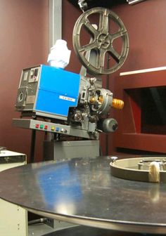 an old movie projector sitting on top of a table in front of a red wall