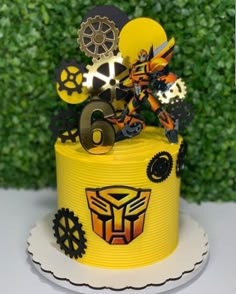 a yellow cake with gears on it and the number six is decorated like a robot