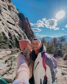 a man and woman taking a selfie on the side of a mountain with mountains in the background