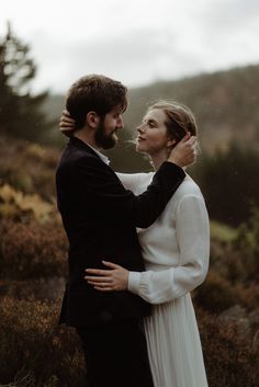 a man and woman embracing each other in the woods