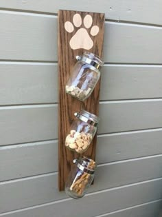 a wooden wall hanging with jars filled with nuts and dog paw prints on the side