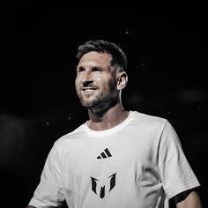 a man standing in front of a black background wearing a white shirt and holding a tennis racquet