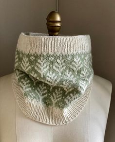 a green and white knitted cowl on top of a mannequin head